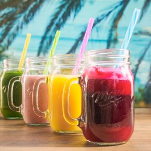 Vibrant fruit juices in mason jars with colorful straws, perfect for a summer refreshment.